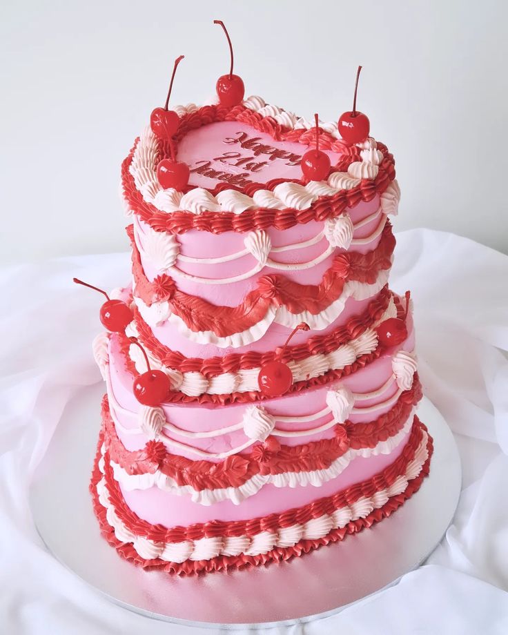 a three tiered cake with hearts and cherries on the top is sitting on a plate