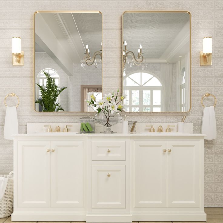 a white bathroom with two mirrors above the sinks and vases on the counter top