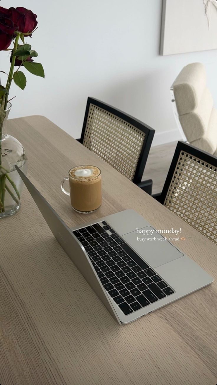 a laptop computer sitting on top of a wooden table next to a cup of coffee