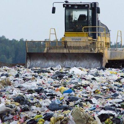 a bulldozer scooping trash into a large pile