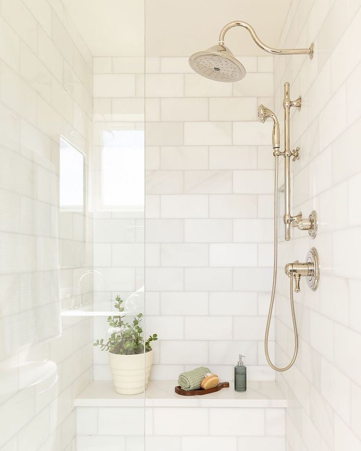 a white tiled bathroom with a shower head