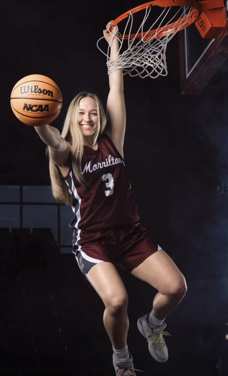 a female basketball player is jumping up to dunk the ball into the hoop with her hands