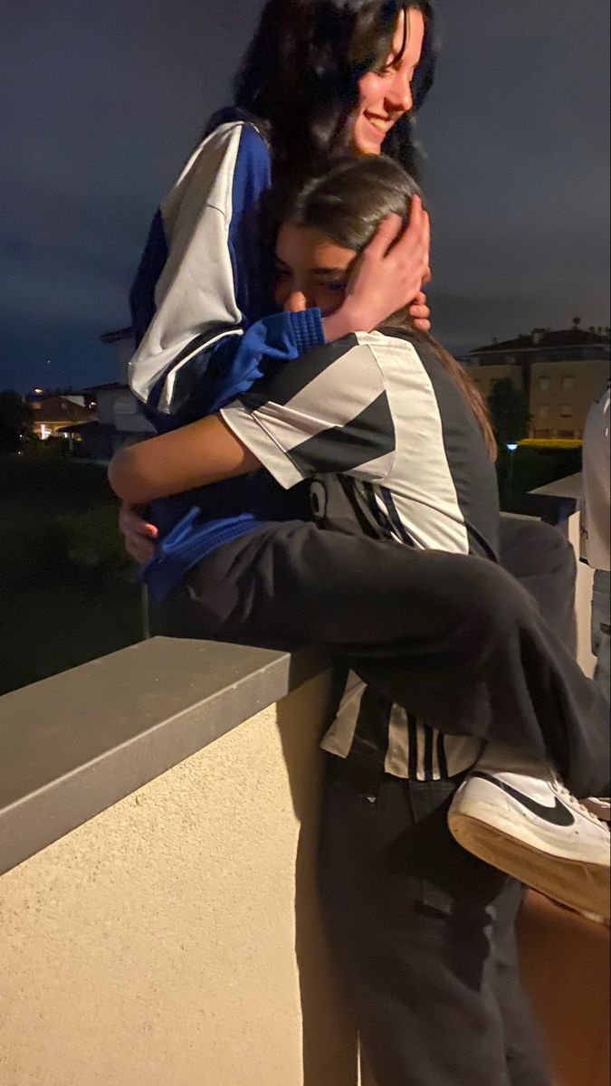 two people hugging each other on a balcony