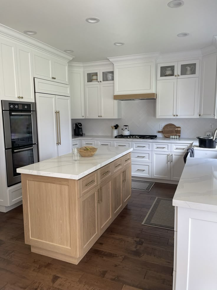 a large kitchen with white cabinets and wood flooring on the countertops, along with an island