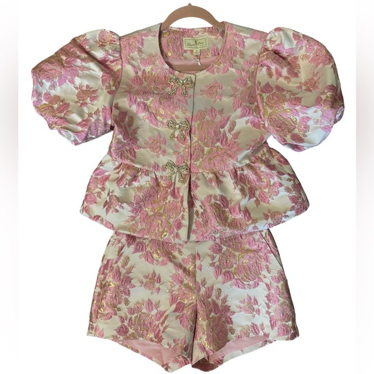 Never Worn, Still Has Tags On It! Purchased For $391 For A Wedding Event And Didn’t End Up Wearing It Bc It Was Too Cold Outside! Absolutely Adorable Two Piece Set! Top Has Puff Sleeves And Bow Buttons With Rhinestones! Set Is A Light Pink With Pink Florals And Gold Shimmer Accents! Both Top And Shorts Are An Xs. Feminine Silk Sets For Summer, Feminine Fitted Silk Set, Feminine Pink Sets For Spring, Fitted Silk Set With Short Sleeves, Pink Wedding Sets For Summer, Elegant Pink Short Sleeve Sets, Fitted Silk Feminine Set, Summer Wedding Pink Sets, Pink Silk Sets For Spring