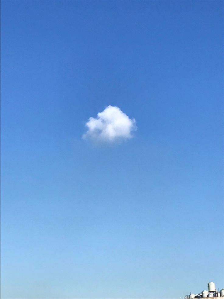 a white cloud is floating in the sky above some buildings and water on a sunny day