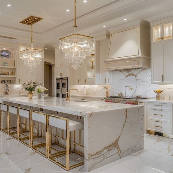 a large kitchen with marble counter tops and gold trim on the cabinets, chandelier above the island