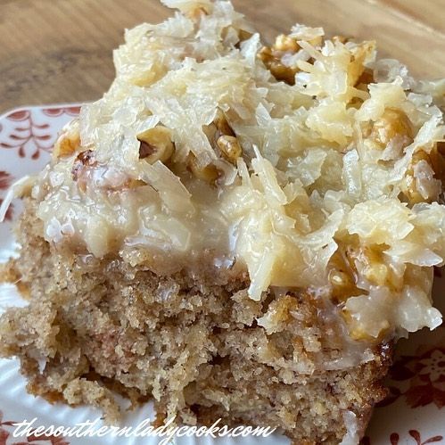 a close up of a piece of cake on a plate with coconut toppings and frosting