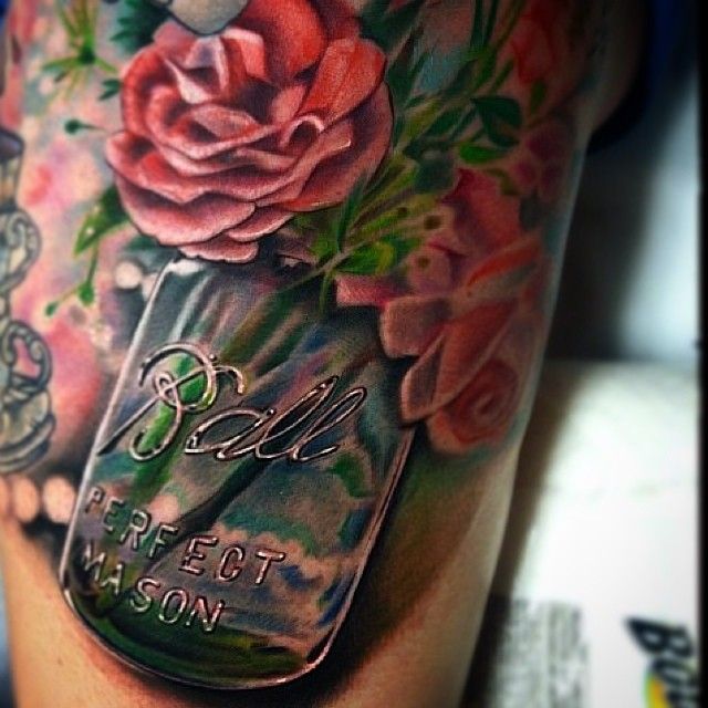 a woman's leg with tattoos on it and flowers in a jar that says ball perfect mason