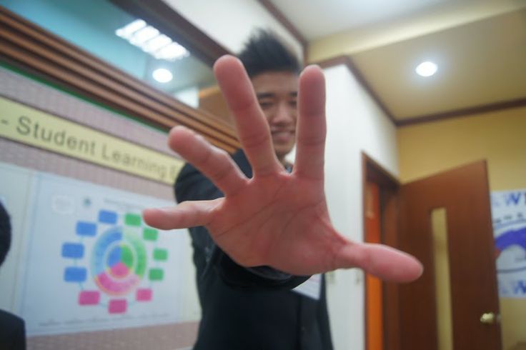 a man is making a hand gesture in front of his students classroom sign and door