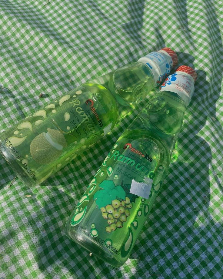 two empty bottles sitting on top of a green table cloth