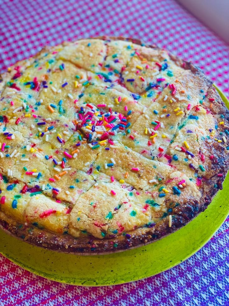 a cake with sprinkles on it sitting on a green plate and checkered table cloth