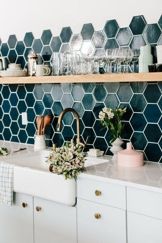 a kitchen with blue hexagonal tiles and white cupboards next to a sink