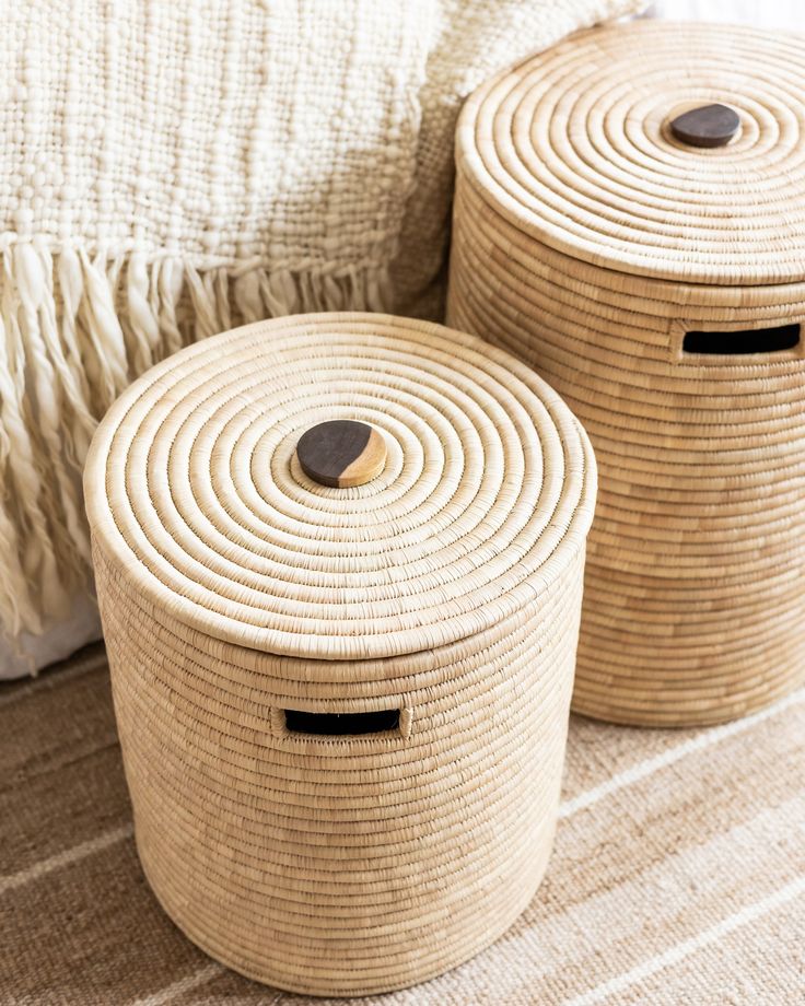 two woven baskets sitting on top of a bed