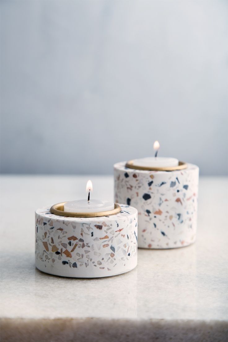 two white candles sitting next to each other on top of a marble countertopstone