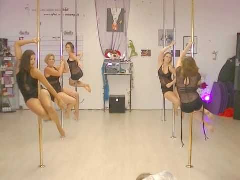 four women in black leotards are hanging upside down on poles and posing for the camera