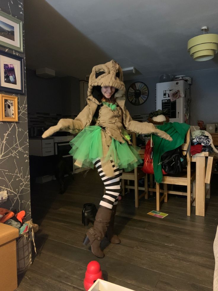 a woman dressed as a cat in a room with wooden floors and walls, holding her arms out to the side