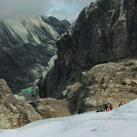 several people hiking up the side of a snow covered mountain