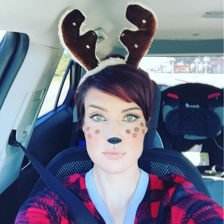 a woman with reindeer antlers on her head sitting in the back seat of a car