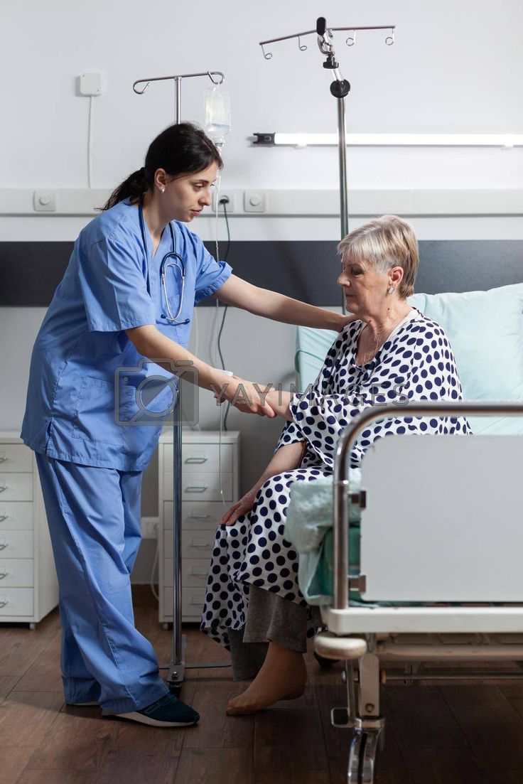 a nurse helping an elderly woman in a hospital bed