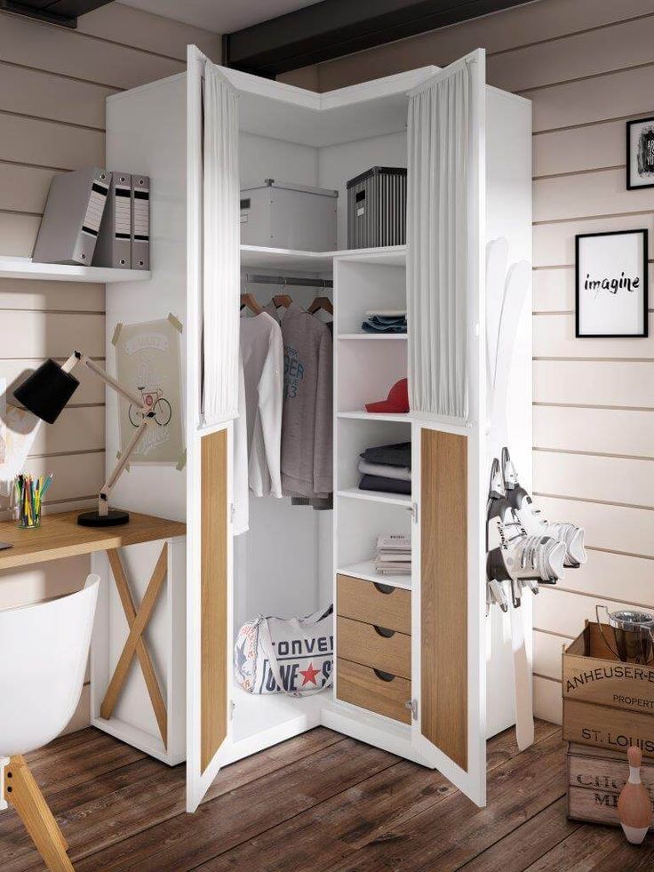 an open closet with clothes hanging on the walls and drawers in it, next to a desk