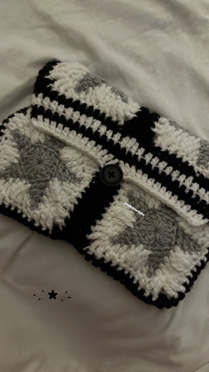 a black and white crocheted bag on a bed with stars in the background