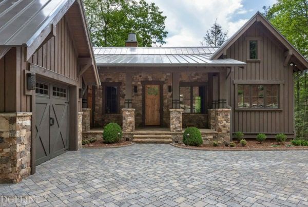 a brick driveway leading to a house with two garages on each side and a stone walkway between them