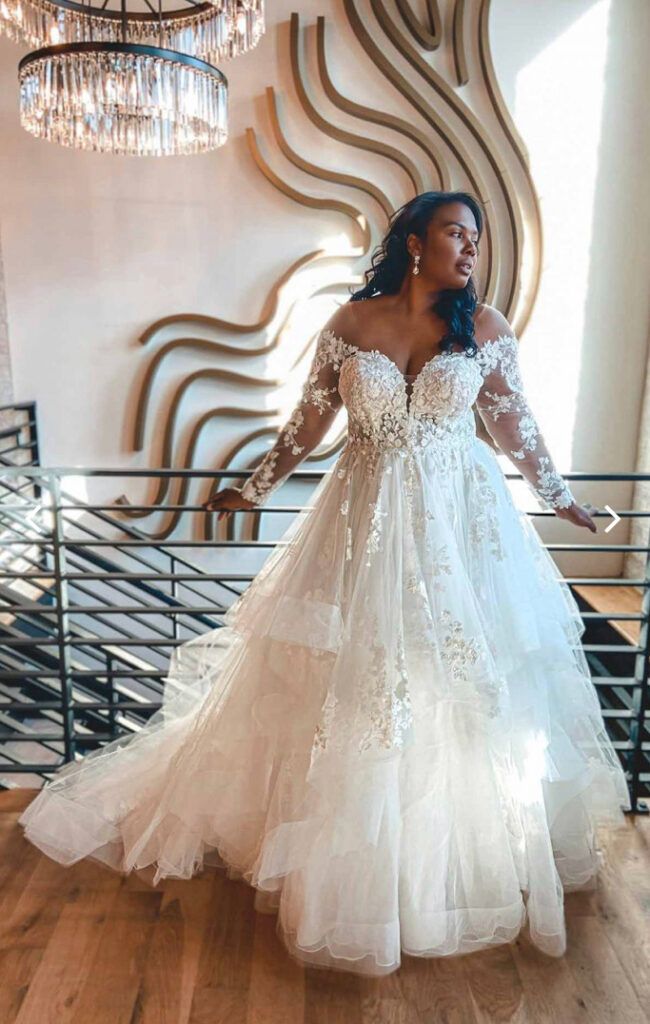 a woman in a white wedding dress standing on a wooden floor with chandelier