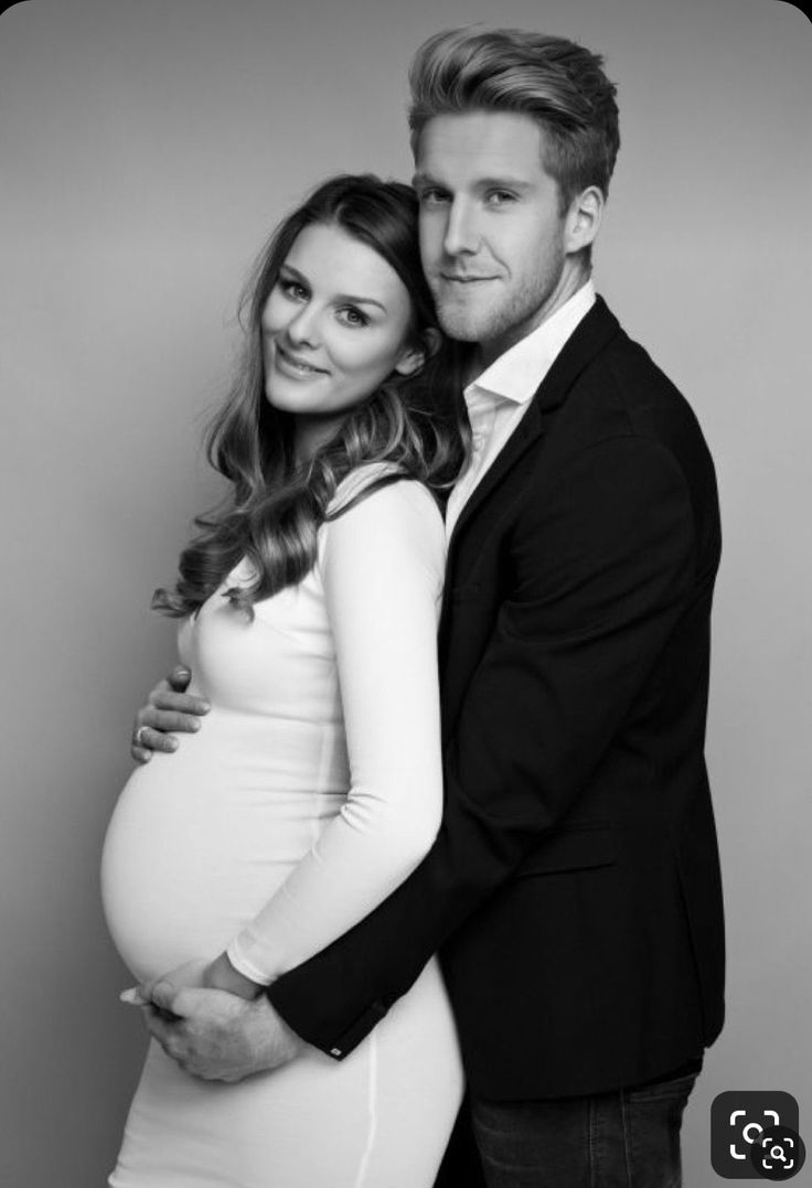 a pregnant couple posing for a black and white photo