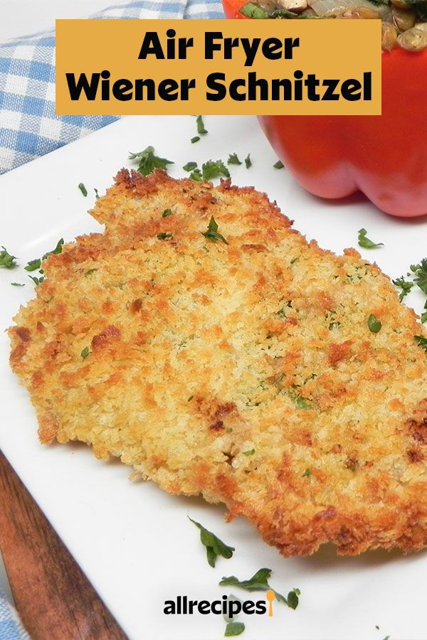 an air fryer schnitzel on a white plate next to a red pepper