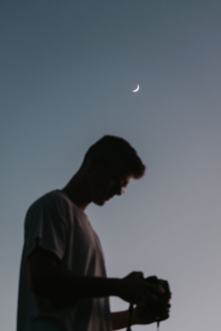 a man standing in front of the moon with his hands on his hips looking at something