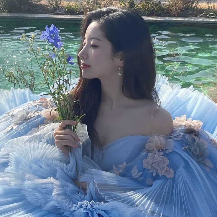 a woman in a blue dress holding flowers