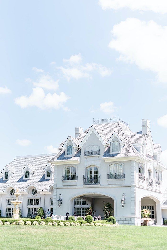 a large white house sitting on top of a lush green field