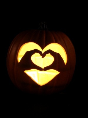 a carved pumpkin with two hands in the shape of a heart