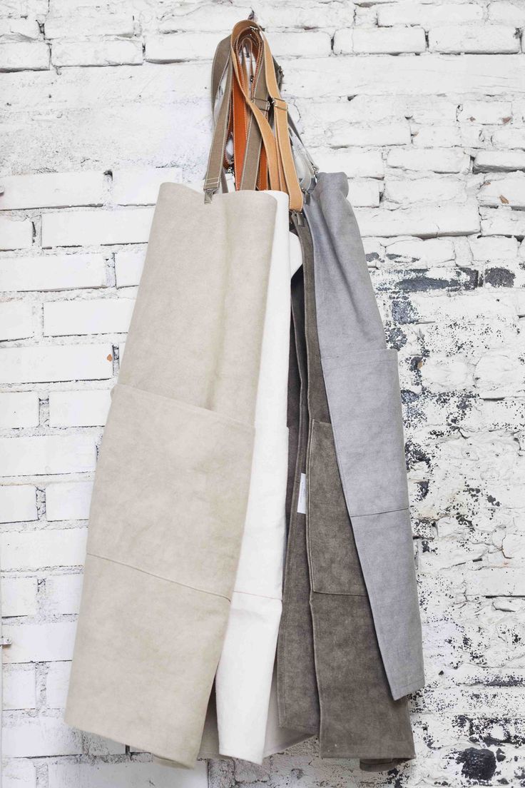 three different colored linens hanging on a white brick wall, one is gray and the other is beige