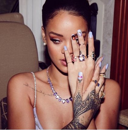 a woman sitting in a chair holding her hands up to her face with tattoos on it