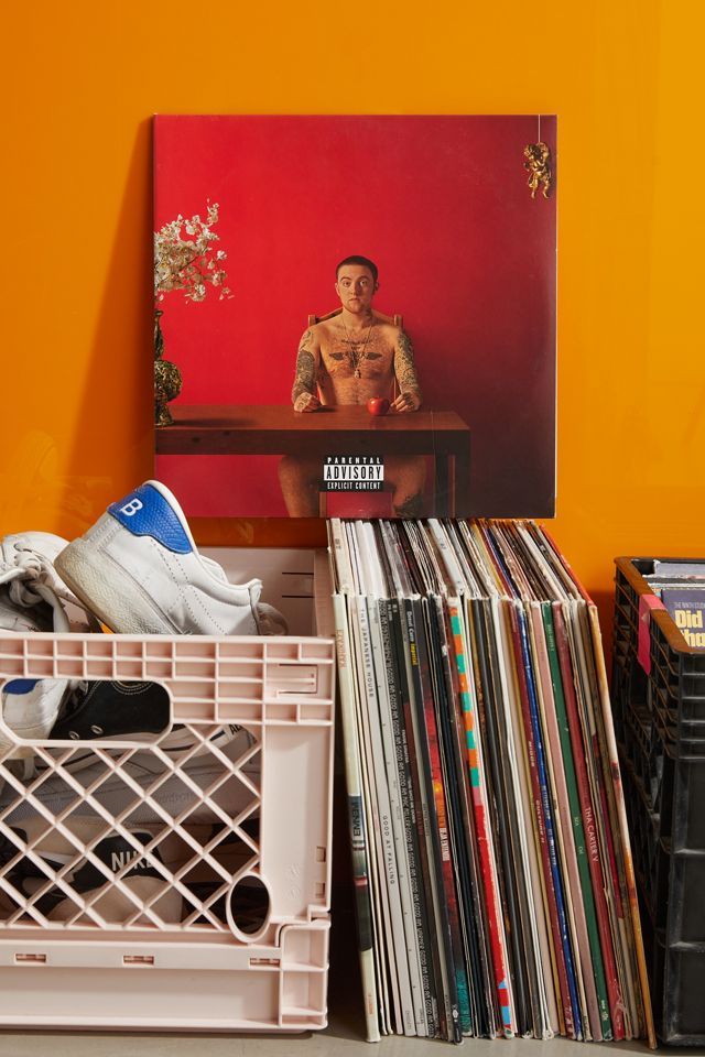 an orange wall with various records and a painting on the wall next to it is a white plastic crate filled with vinyl records