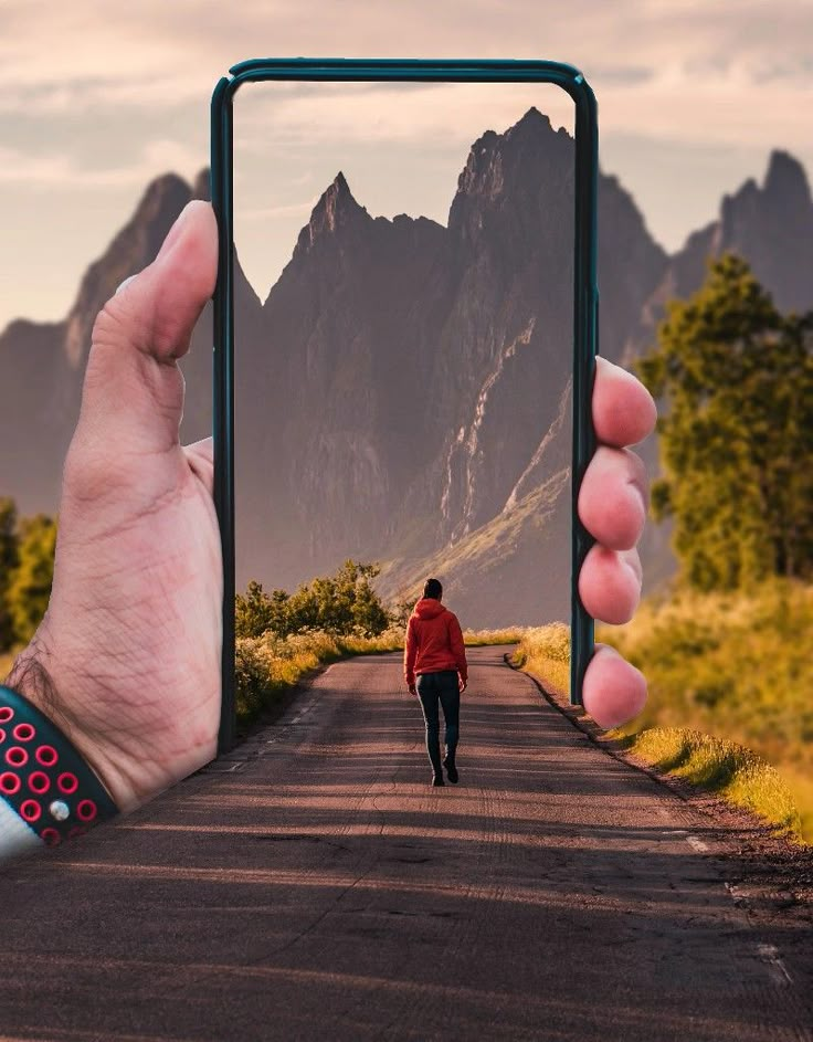 a person taking a selfie with their cell phone in front of them on the road