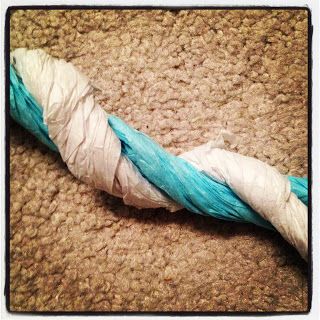 a blue and white piece of cloth on the ground next to a roll of yarn