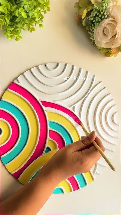 a person holding a paintbrush in front of a paper plate with circles on it