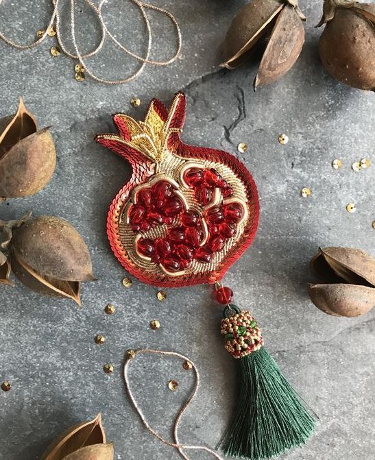 the pomegranate has been made with gold and red beads, which are hanging from