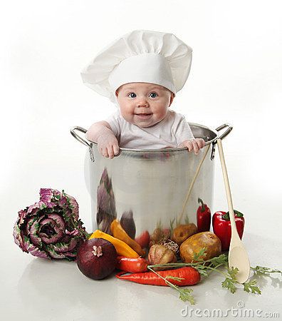 a baby in a chef's hat is sitting in a pot filled with vegetables