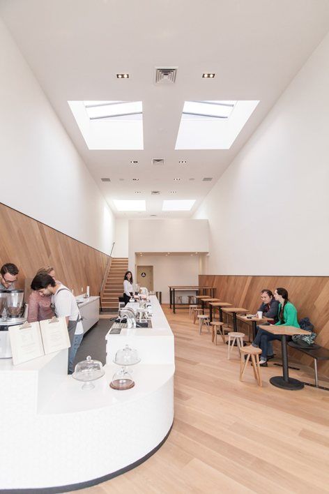 people sitting at tables in a cafeteria with white tablecloths on them and wooden walls