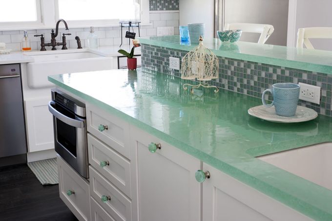 a kitchen with green counter tops and white cabinets, along with a dishwasher