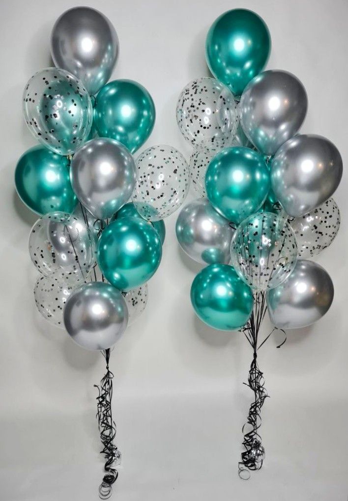 a bunch of silver and teal balloons are in the air