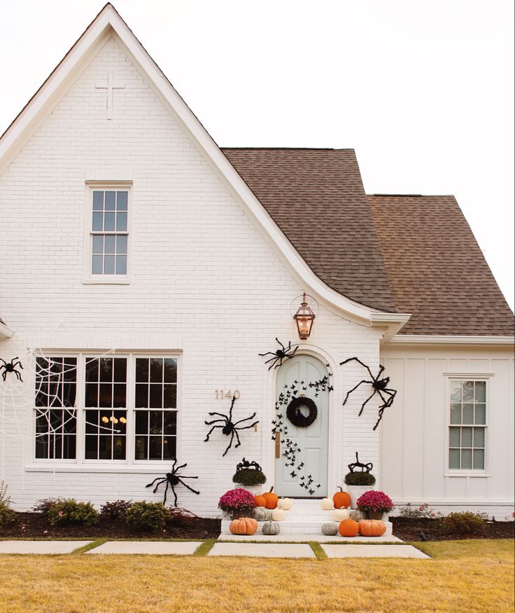 a white house decorated for halloween with pumpkins and spider decorations