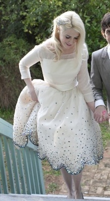 a man and woman dressed in formal wear walking down a bridge holding hands with each other