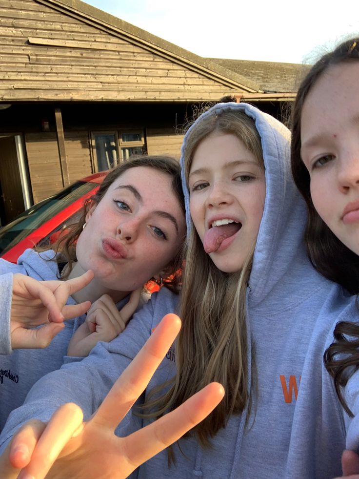 three girls posing for the camera with their fingers in the shape of two peace signs