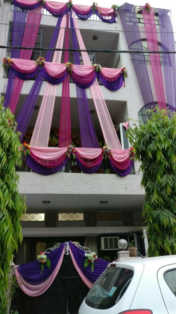 a car parked in front of a building with purple and pink drapes hanging from it's windows