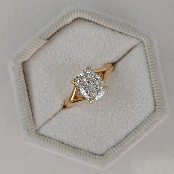 an engagement ring with a cushion cut diamond in it's display case on a white background